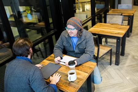 Ted Kluck, assistant professor of communication arts, meets with a student about screen writing in Modero Coffee Roasters. - Photo by Kristi McMurry Woody