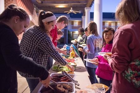Students and their families feast on burgers and hot dogs at the Residence Life Grill Out during Sibling Weekend.  - Photo by David Parks