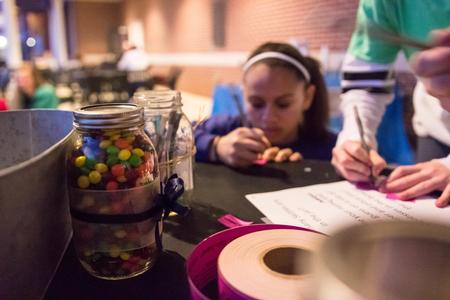 Students' family members guess how many Skittles are in the jar at the Residence Life Grill Out during Sibling Weekend. - Photo by David Parks
