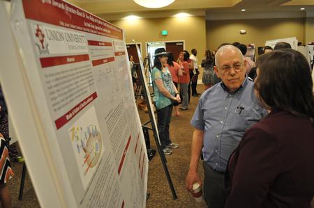 Robert Duncan, visiting instructor of chemistry, talks with a student about her research project at the annual Scholarship Symposium. - Photo by Elizabeth Wilson