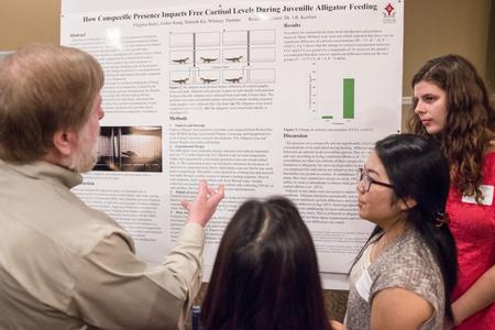 Members of the biology department discuss a project during the Scholarship Symposium poster presentations in the Carl Grant Events Center. - Photo by David Parks