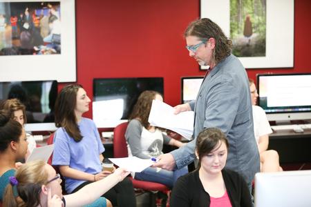 Ted Kluck, assistant professor of communication arts, passes back papers written for his class.  - Photo by Kristi McMurry Woody
