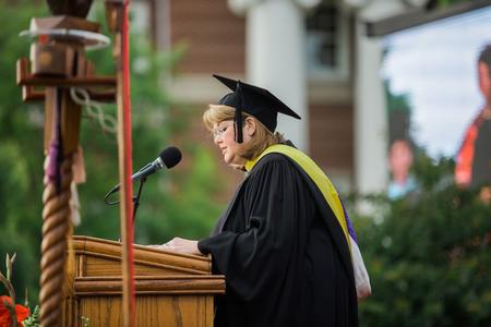 Melissa Moore, professor of library sciences, reads scripture at the beginning of spring commencement services.  - Photo by Kristi McMurry Woody