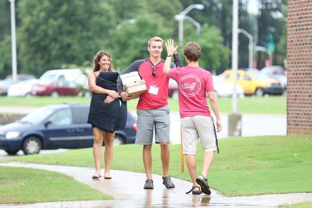 A new student high-fives his new residence advisor as he carries his things to his room. - Photo by Kristi McMurry Woody