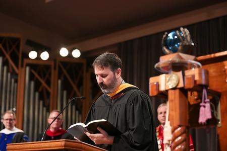 Cam Tracy, web development agent and staff member of the year, reads scripture during Convocation. - Photo by Kristi McMurry Woody