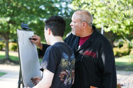 Chris Nadaskay, university professor of art, teaches a drawing class outside and demonstrates a technique for Nic Linn, senior history major. - Photo by Kristi McMurry Woody