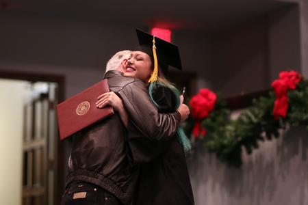 Sydney Fly, interdisciplinary studies graduate, hugs family after receiving her diploma during fall commencement.  - Photo by Kristi McMurry Woody