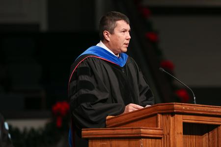 Andrew Tiger, professor of management, delivers the scripture reading during fall commencement. - Photo by Kristi McMurry Woody