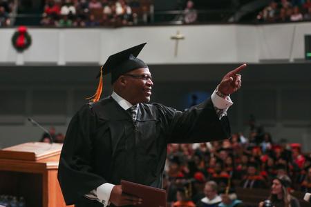 Ulylanders Kent, BSOL graduate, waves to family and friends after receiving his diploma at fall commencement.  - Photo by Kristi McMurry Woody
