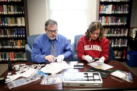 Gavin Richardson, professor of English, works with Beth Adams, senior English major, on a project to clean and catalogue a rare coin collection. - Photo by Kristi McMurry Woody