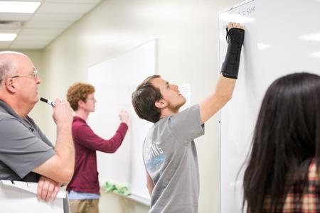 Bryan Dawson, professor of mathematics, supervises his students working math problems on the board during class. - Photo by Kristi McMurry Woody