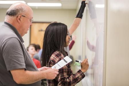 Bryan Dawson, professor of mathematics, helps his students as they work math problems during class.  - Photo by Kristi McMurry Woody