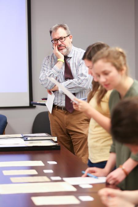 Gavin Richardson, professor of English, watches as his students examine authentic 16th century Bible leaves for an exercise in his class.  - Photo by Kristi McMurry Woody