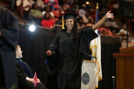 Asia Wilson, BSOL graduate, waves to friends and family as she walks across the stage to receive her diploma.  - Photo by Kristi McMurry Woody
