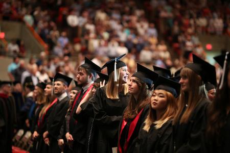 McKenna Carter, public relations graduate, looks back at the crowd to find her friends at family at the beginning of spring commencement. - Photo by Kristi McMurry Woody