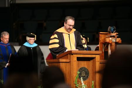 Brian Foster, assistant professor of nursing, delivers the invocation for summer commencement. - Photo by Kristi McMurry Woody