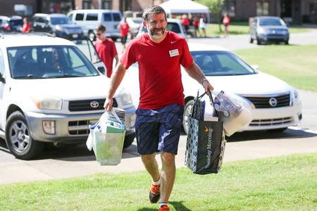 Josh Williams, associate professor of chemistry, helps carry a new student's belongings during move-in day. - Photo by Kristi McMurry Woody