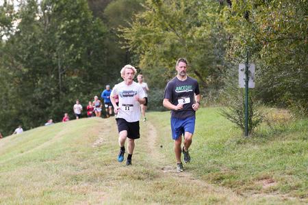 Layton Estes, accounting major, and Michael Schiebout, associate professor of biology, run the 5k on the Union Trails during Family Weekend.  - Photo by Kristi McMurry Woody