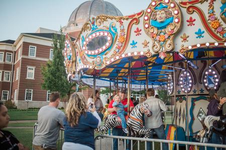 Josh Simmons, director for eLearning success and media services, and his son enjoy the carousel during Family Weekend Union Night.  - Photo by Kristi McMurry Woody