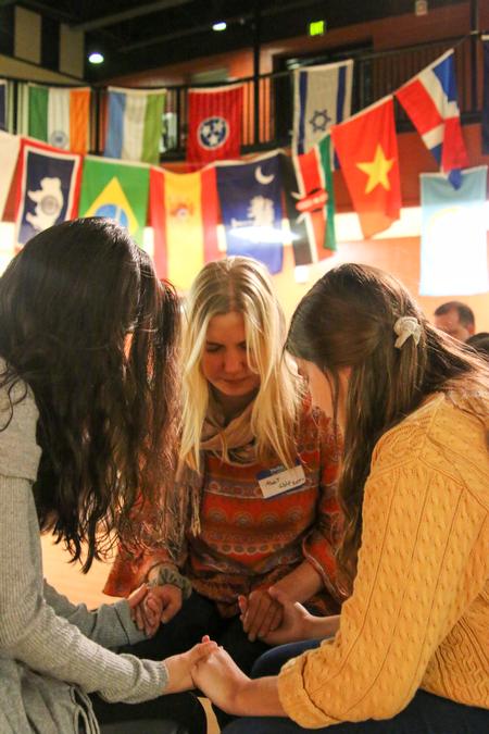 Sophomore ceramics major Abby Wolfzorn prays over upcoming Go Trips during the Go Trip team reveal. - Photo by Hannah Heckart