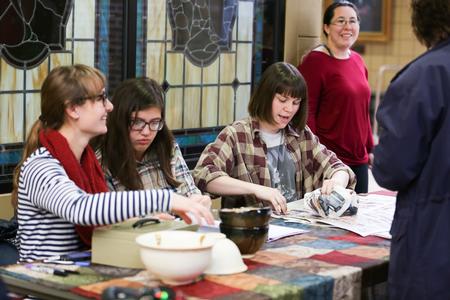 Megan Peden, art department shop technician, and Candace Gooch, art academic secretary, along with art students wrap up purchases at the annual Christmas Pottery Sale. - Photo by Kristi McMurry Woody