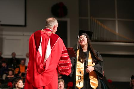 Songhyun Kim, art studio graduate, receives her diploma from Dub Oliver, president of the university.  - Photo by Kristi McMurry Woody