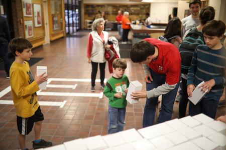 Georg Pingen, associate professor of engineering, hands a Dub Oliver bobblehead to his son during the bobblehead giveaway event. - Photo by Kristi McMurry Woody
