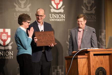 Pat and George Guthrie accept a beautiful customized cutting board as a gift from the School of Theology and Missions. - Photo by Kristi McMurry Woody