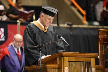Robert Simpson, associate vice president for business services, prays at the beginning of spring commencement services.  - Photo by Kristi McMurry Woody