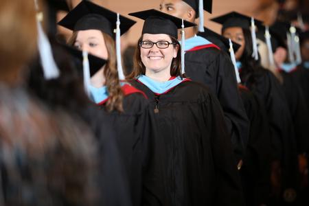 Kelley Jones, master of arts in education graduate, smiles with her fellow graduates as she makes her way to her seat during summer graduation. - Photo by Kristi McMurry Woody