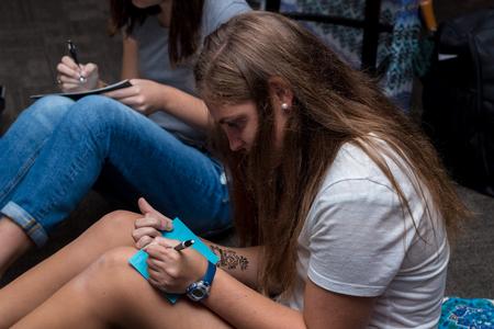 Jesse Greer, junior English major, participates in writing letters to families in need of prayer during Henna Night. - Photo by Nikki Grim