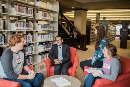 Joseph Xu, assistant professor of marketing, chats with students in the library. - Photo by Kristi McMurry Woody