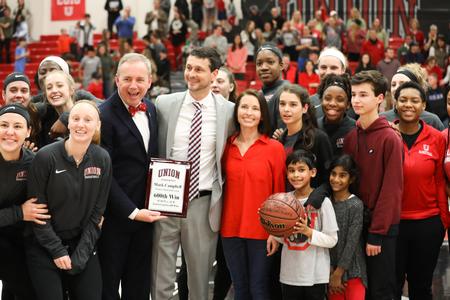 Dub Oliver, president of the university, poses with Mark Campbell, head women's basketball coach, his family and players after celebrating Campbell's 600th career win. - Photo by Sarah Palmer Goff