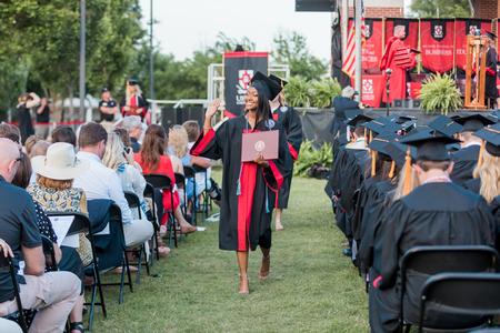 Graduates head back to their seats after receiving their diplomas during spring commencement. - Photo by Kristi McMurry Woody
