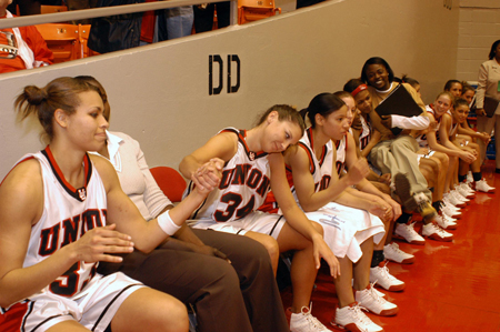 Seniors Stephanie Clark (33) and Molly York (34) congratulate each other after Union semifinal win in the NAIA Women's National Tournament.  The remainder of the team sits during the final four trophy presentation. - Photo by Morris Abernathy