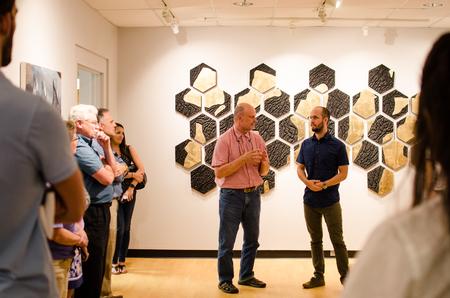 Lee Benson, university professor of art and department chair, talks with alum Caleb Booth during his gallery reception in the Union Art Gallery. - Photo by Jess Newendyke