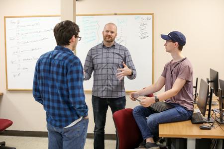 Brian Glas (center), assistant professor of computer science, talks with his students in the computer lab. - Photo by Kristi McMurry Woody