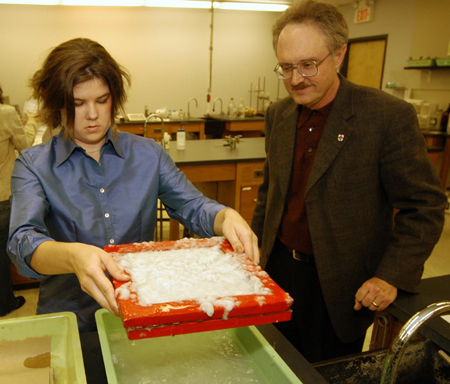 Senior Melanie Rickett takes the tray of paper pulp to the next step of the paper making process, as chemistry professor Jimmy Davis supervises. - Photo by Morris Abernathy