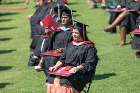 Union University graduates sit with their diplomas as their classmates cross the stage. - Photo by Kristi McMurry Woody