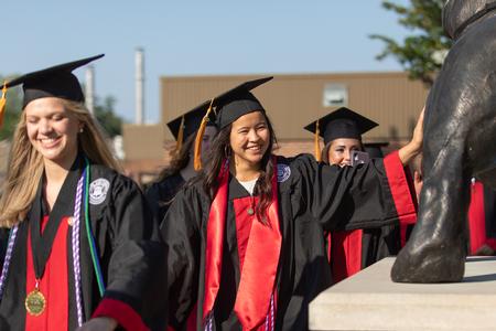 Students pat Buster on the way to the Great Lawn for graduation. - Photo by Kristi McMurry Woody