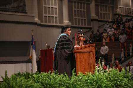 Linda Campbell, assistant dean and program director of the master of arts in education, reads from Romans 12 during summer graduation. - Photo by Kristi McMurry Woody