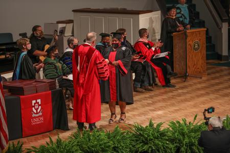 Students walk across the stage at summer graduation to receive their diplomas. - Photo by Kristi McMurry Woody