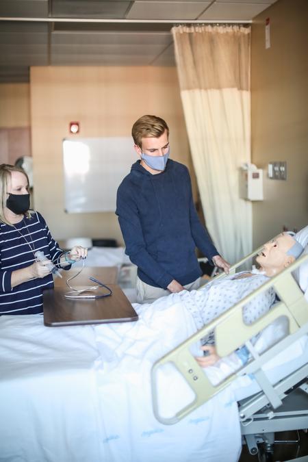 Jennifer Delk, assistant professor of nursing, and Nathanael Dean, senior nursing major, work in one of the simulation labs in Providence Hall. - Photo by Kristi McMurry Woody