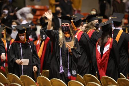 Graduates wave to family as they find their seats at the beginning of Fall Graduation. - Photo by Kristi McMurry Woody