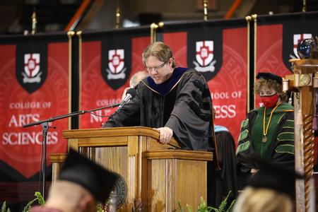 Steve Halla, associate professor of art and current faculty member of the year, opens Fall Graduation with a prayer.  - Photo by Kristi McMurry Woody