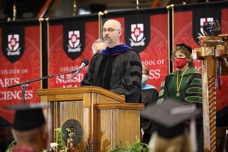 Joshua Veltman, professor of music, reads scripture during Fall Graduation. - Photo by Kristi McMurry Woody