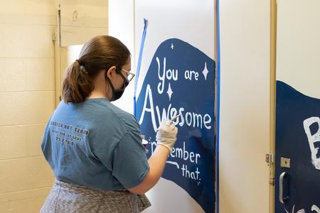 Students paint inspirational messages on in a school bathroom during Campus and Community Day. - Photo by Naomi Mengel