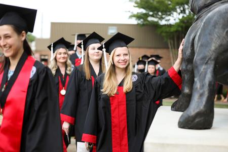 Emily Chapman, art graduate, pats the Buster statue on her way to the Great Lawn for spring commencement. - Photo by Kristi McMurry Woody