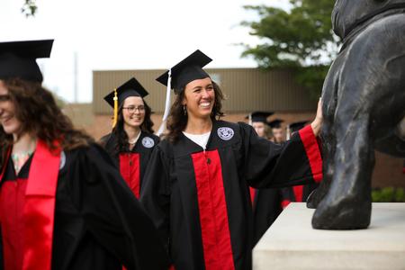 Delaney Sain, public relations graduate, pats the Buster statue on her way to the Great Lawn for spring commencement. - Photo by Kristi McMurry Woody