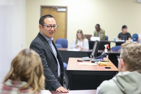 Joseph Xu, associate professor of marketing, talks with students about an assignment before class. - Photo by Kristi McMurry Woody
